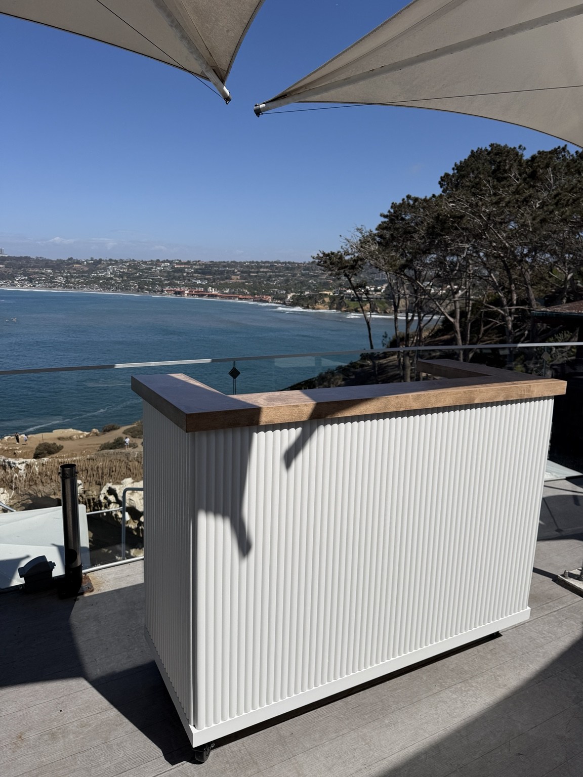 NEED's white fluted mobile bar with a wooden counter overlooking the San Diego coastline