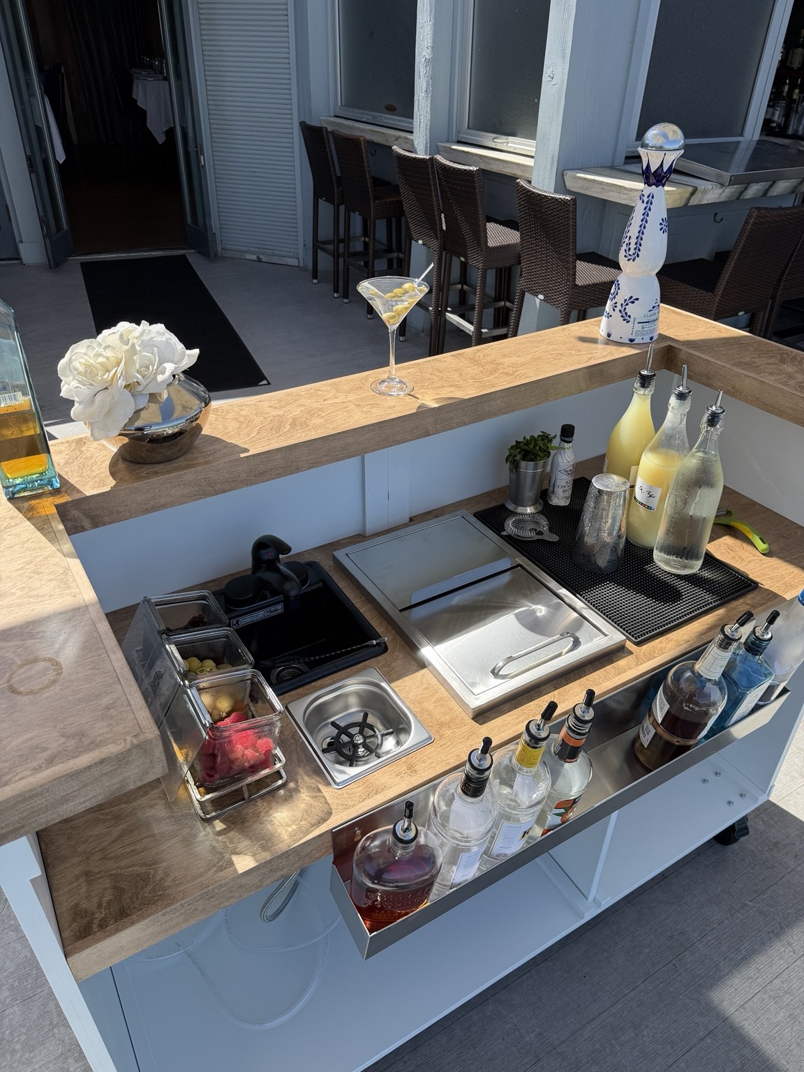 The bar's wood workspace, sink, pitcher rinser, ice well and prepared garnishes